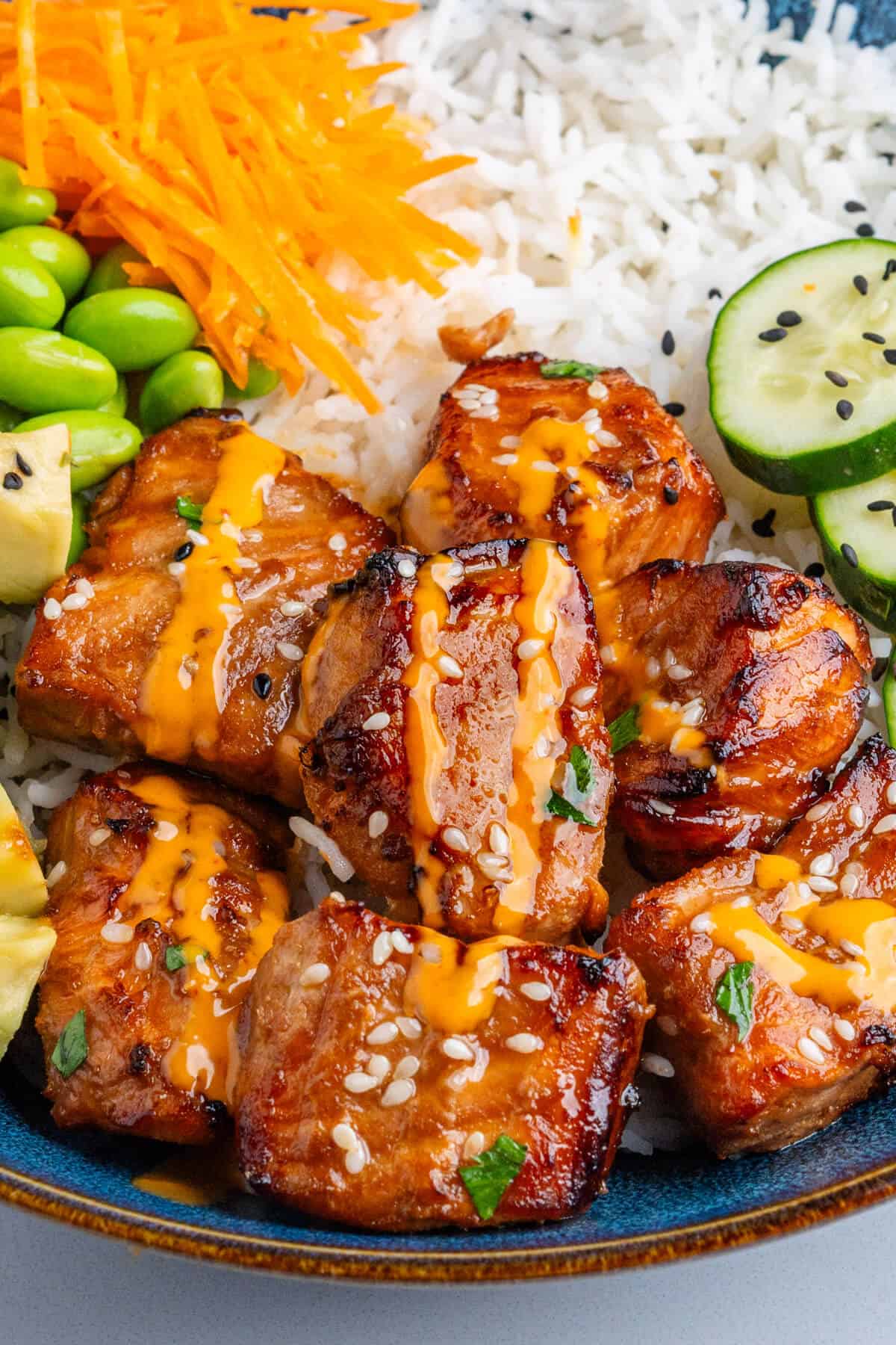 Close up of salmon in a bowl topped with sriracha aioli