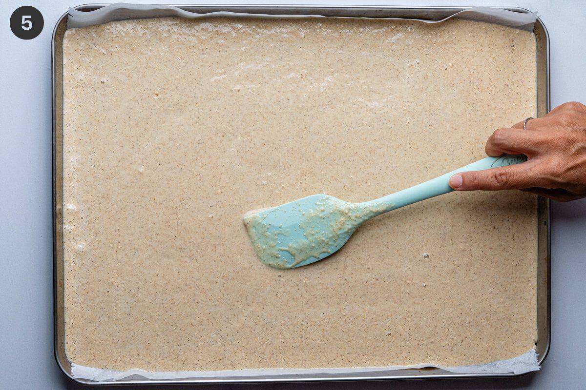 Pancake batter being spread out on a baking tray