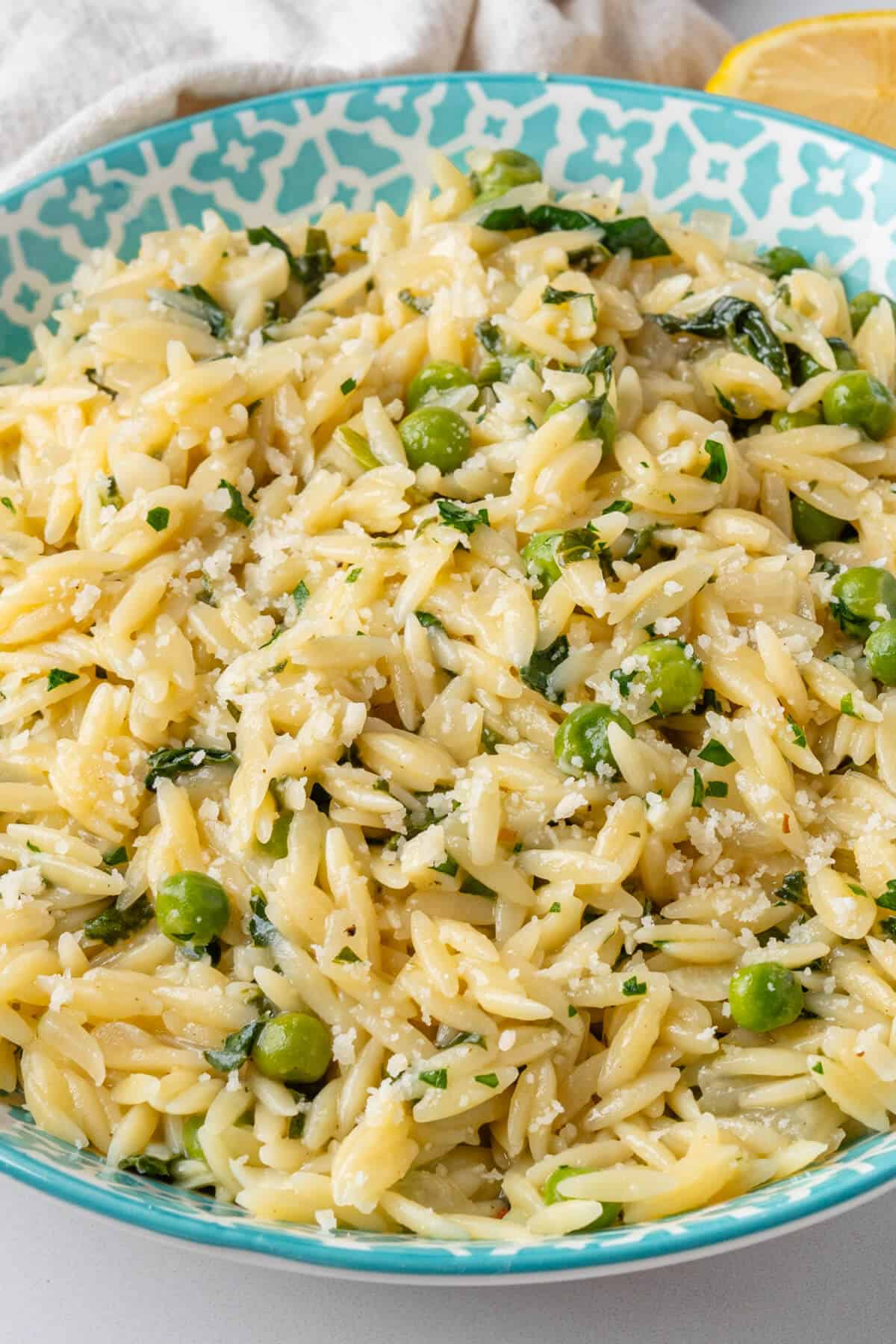 Bowl of orzo with peas and spinach topped with parmesan