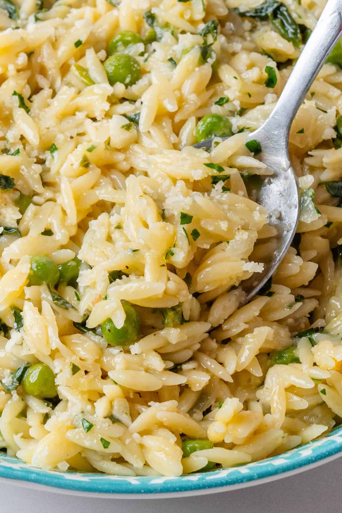 Close up of spoon coming out of a bowl of orzo