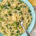 Spoon in a bowl of lemon orzo with peas and spinach