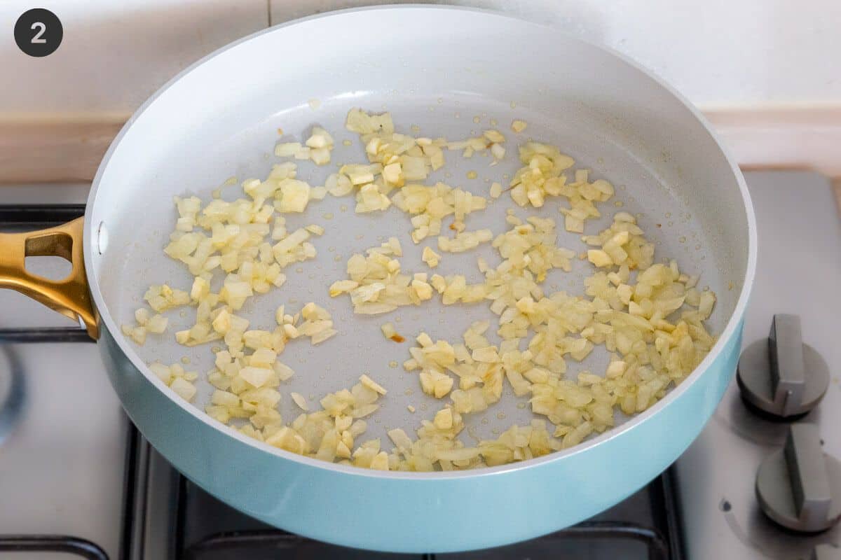 Onion being sautéed in a large pan