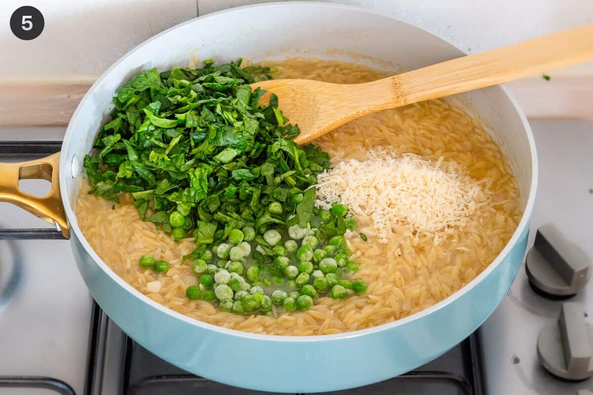 Spinach, peas and parmesan cheese added to a large pan