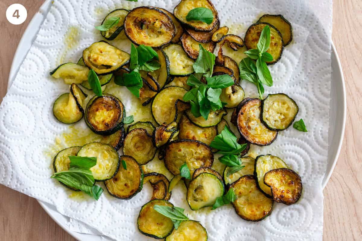 Fried zucchini with fresh basil leaves on paper towels