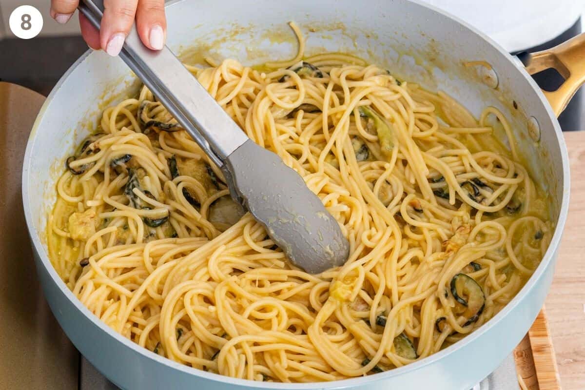 Stirring of pasta with tongs to make a creamy sauce