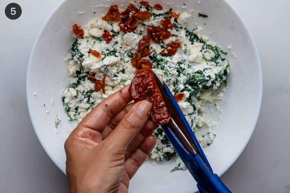 Sun dried tomatoes being chopped up with scissors