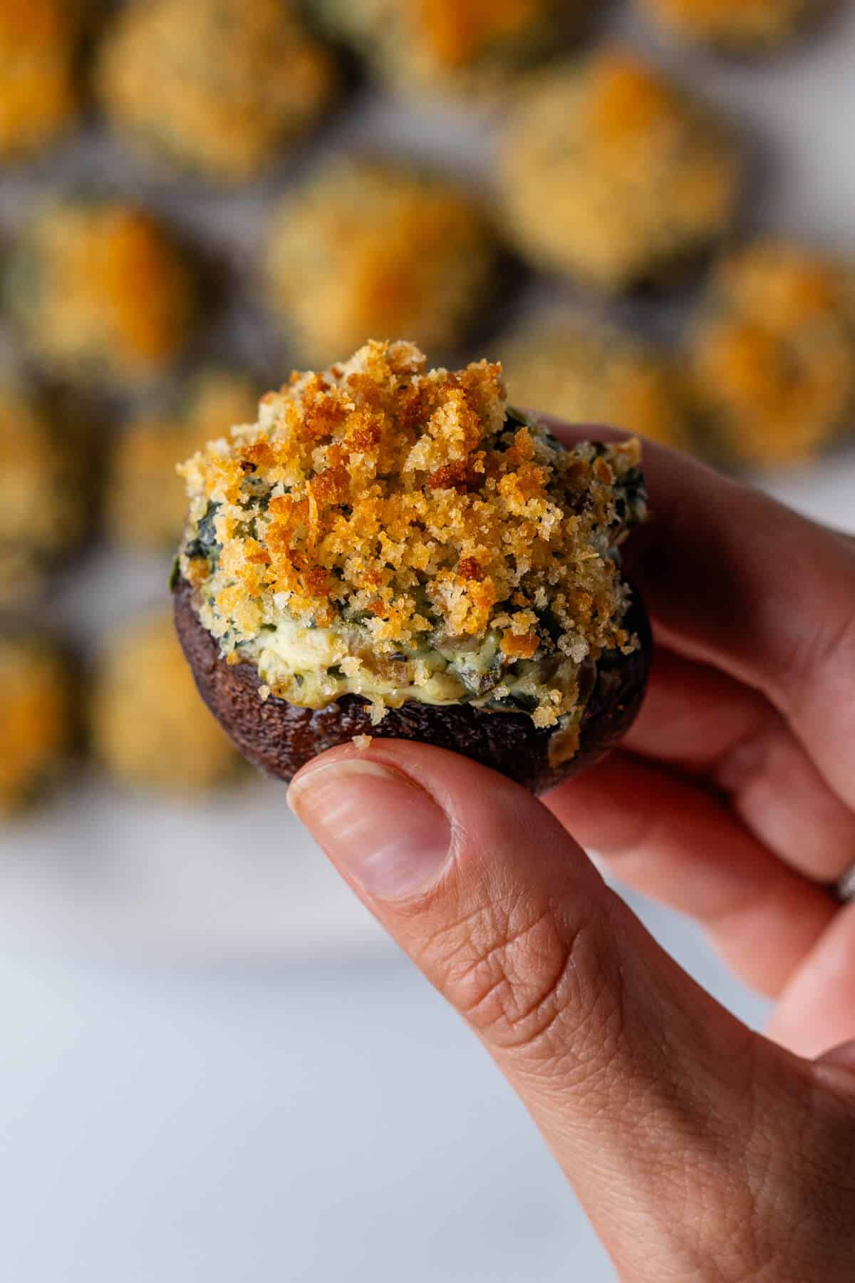 Close up of a piece of stuffed mushrooms being held up