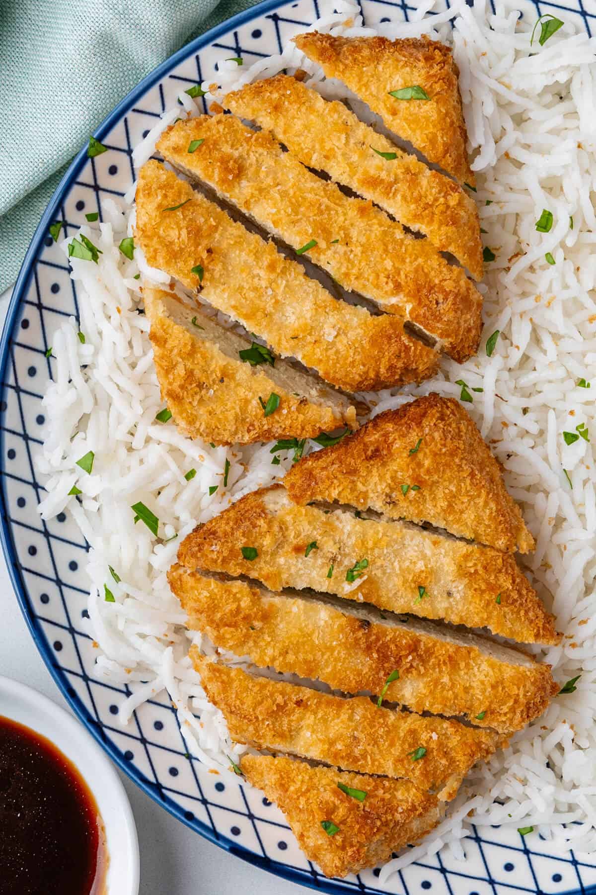 Two pieces of tofu katsu sliced on a plate of rice