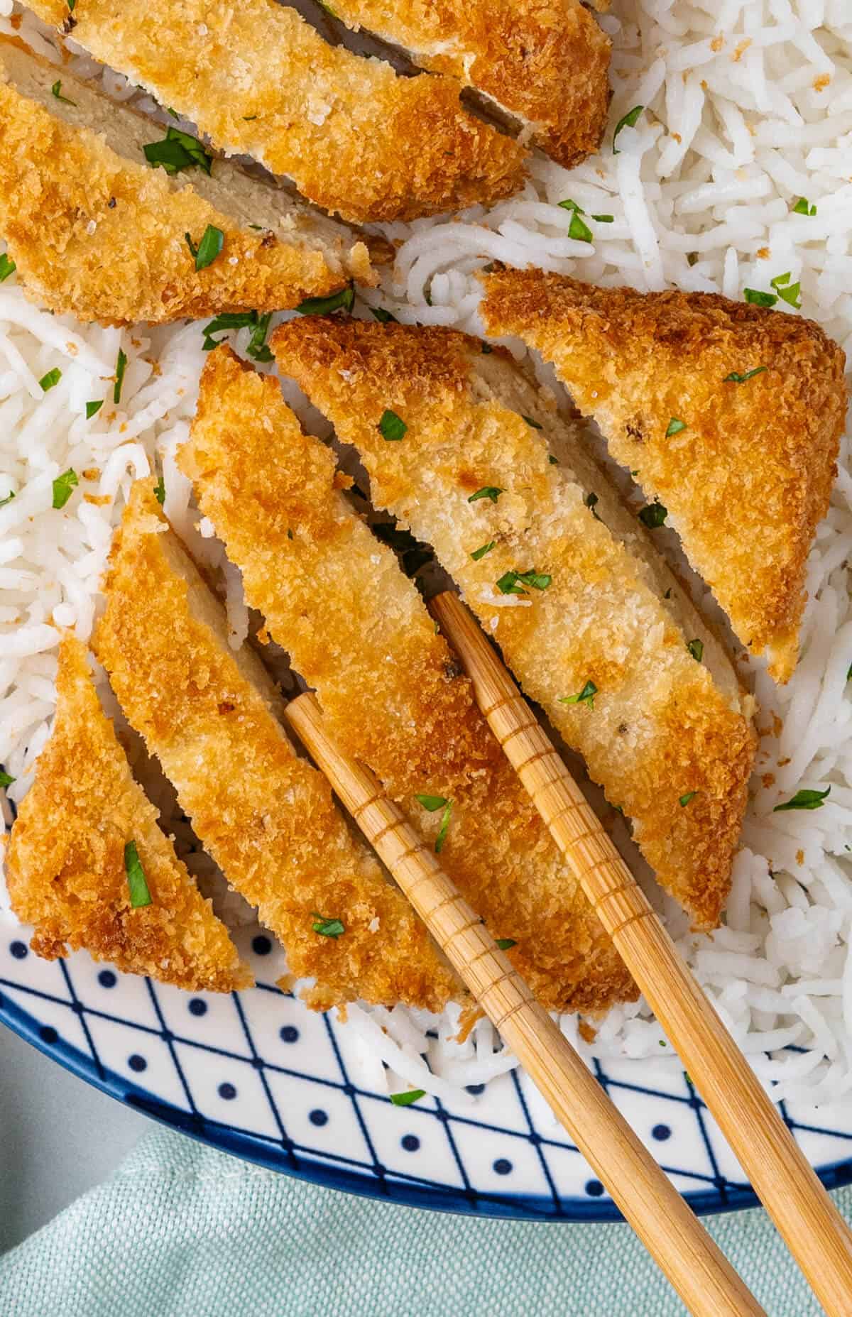 Chopsticks picking up a slice of tofu katsu