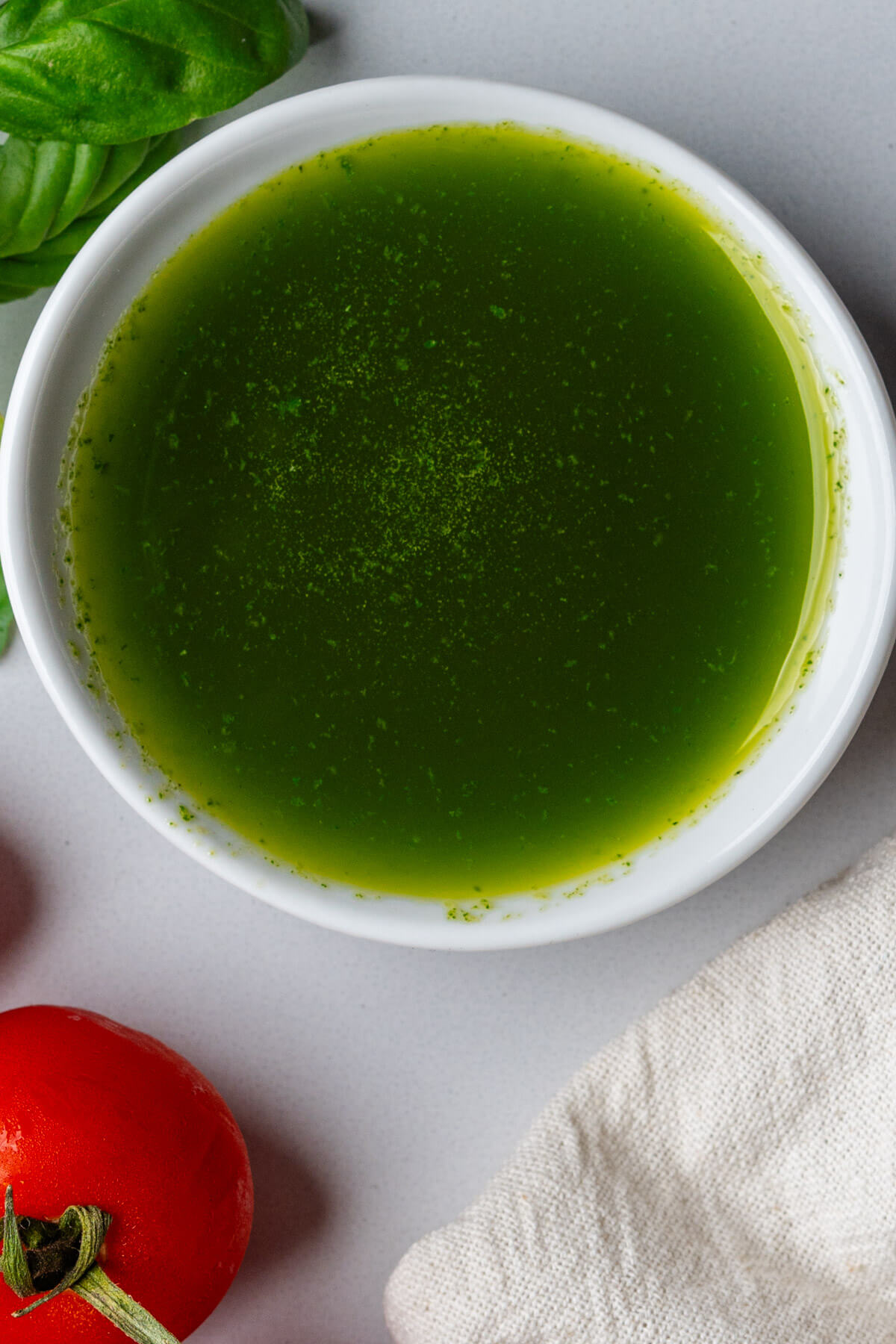 Ramekin of oil with tomatoes and basil on the side