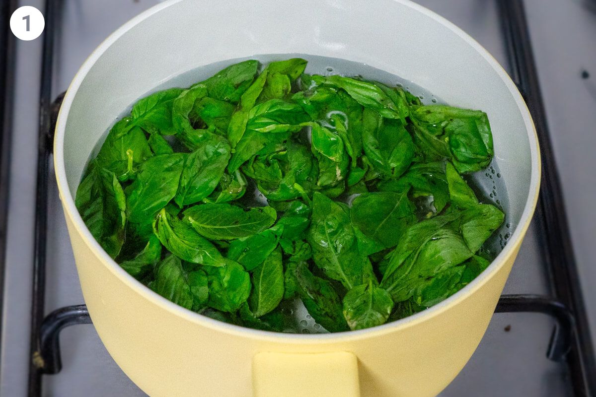 Basil being blanched in a pot of boiling water