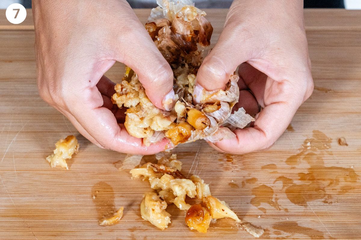 Roasted garlic being squeezed out with hands