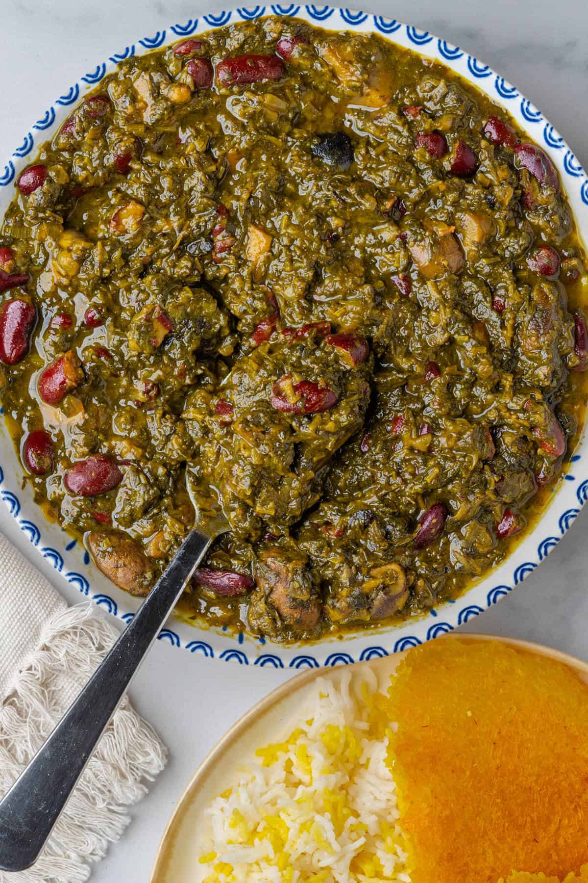 Persian Herb Stew in a bowl with rice and tahdig on the side