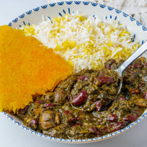 Spoon in a bowl of Ghormeh Sabzi with rice and saffron tahdig