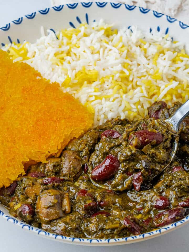 Spoon in a bowl of Ghormeh Sabzi with rice and saffron tahdig