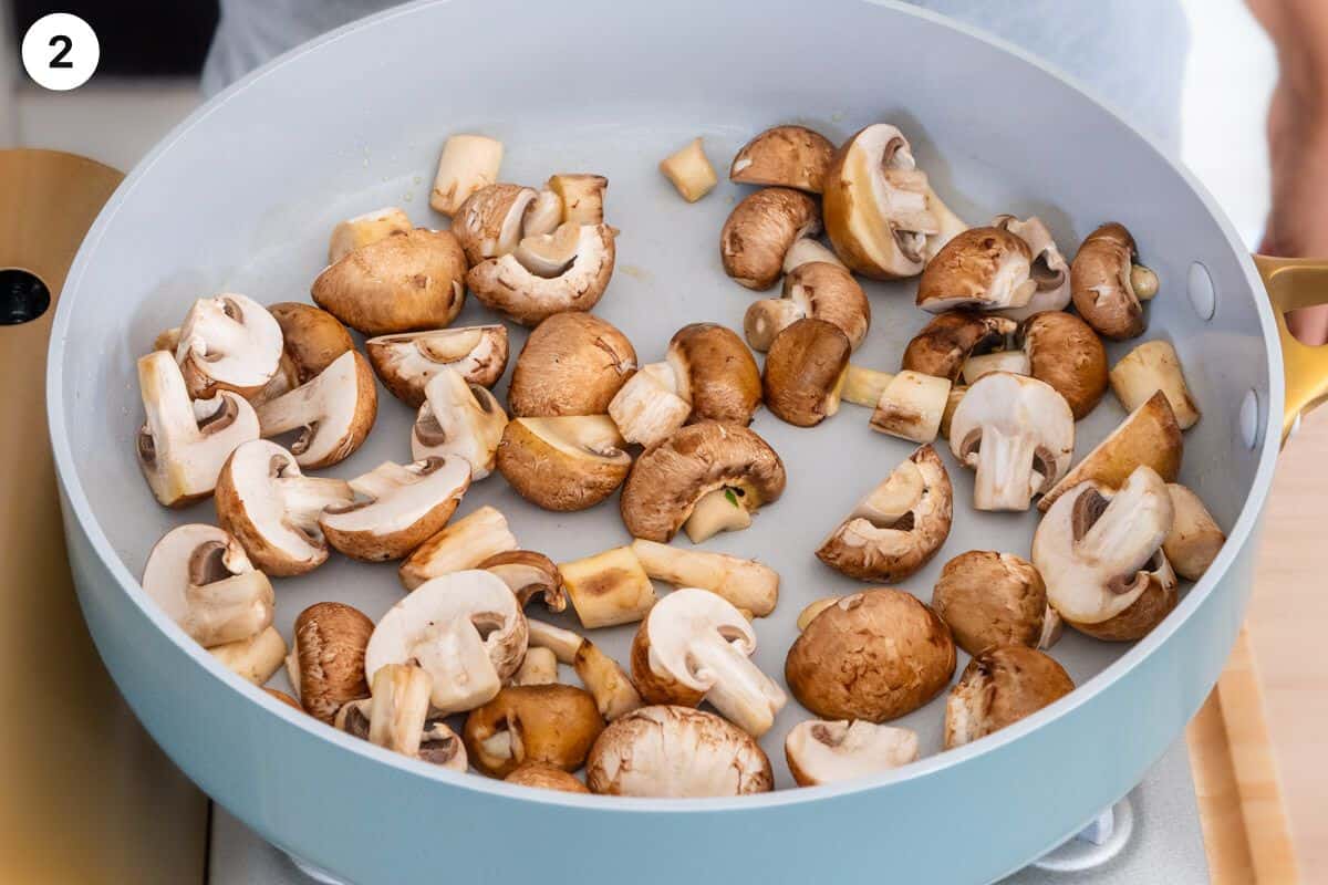 Mushrooms being sautéed in a large pan