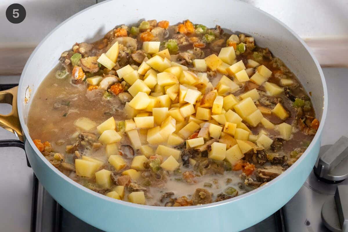 Potatoes, stock and milk added to the pan