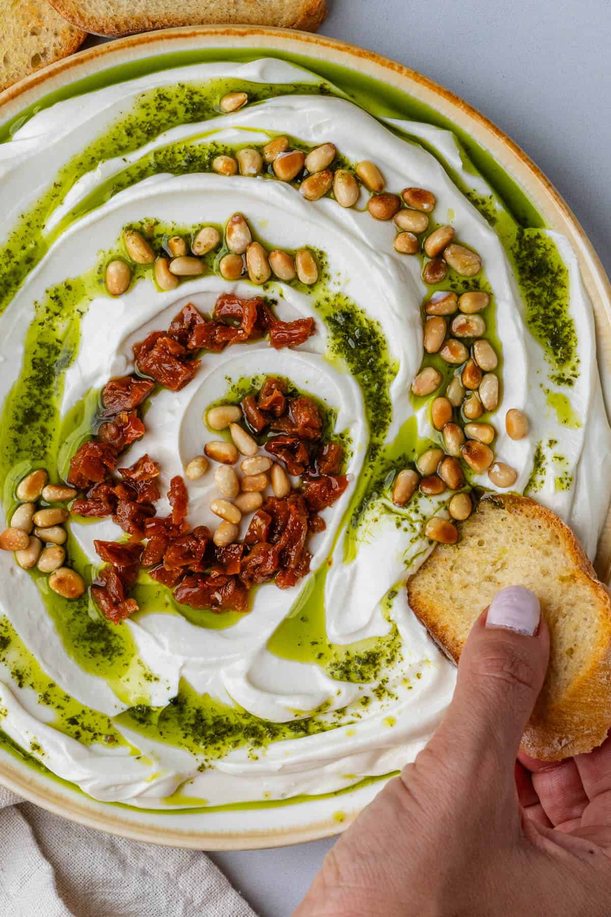 Piece of bread being dipped into bowl of whipped ricotta