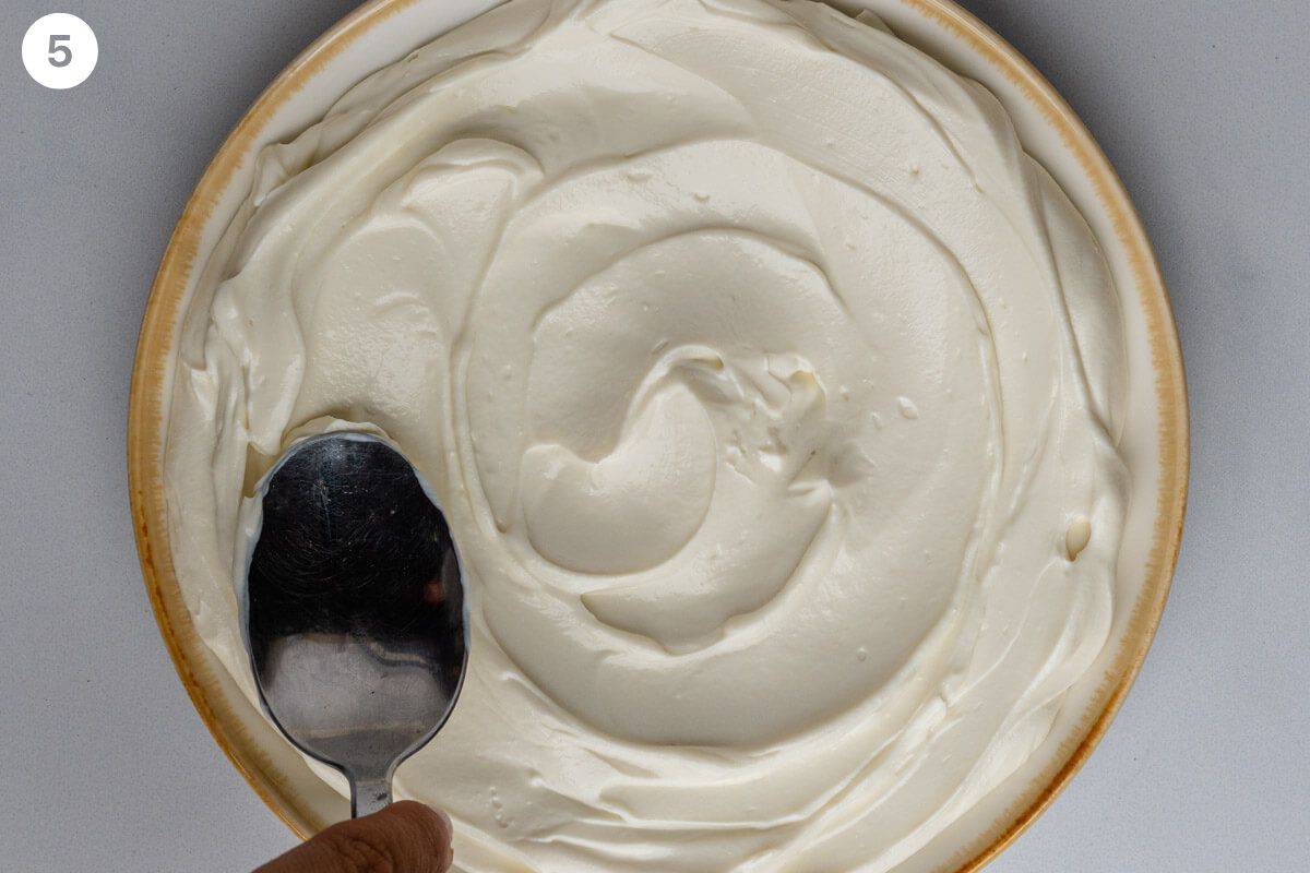 Back of spoon flattening ricotta in a bowl