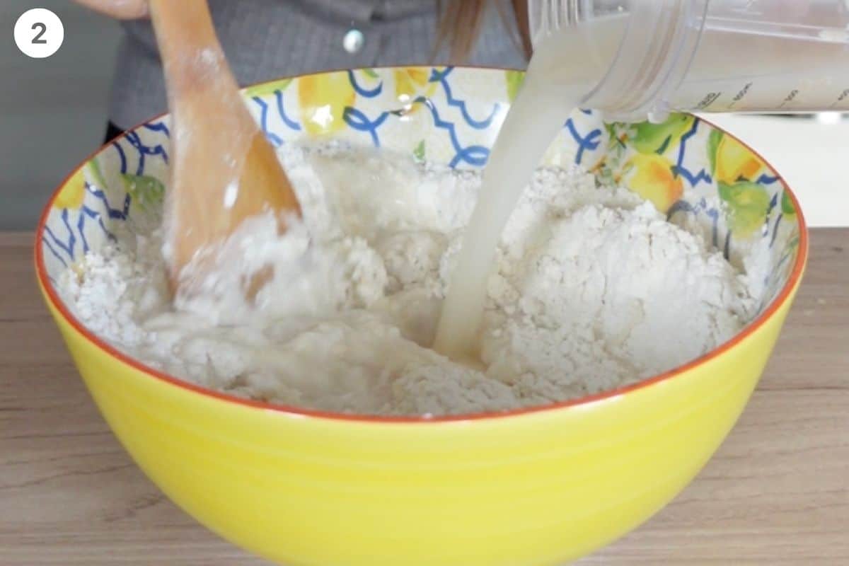 Water with yeast being poured into flour bowl