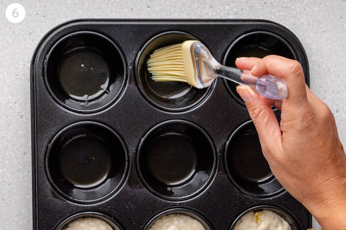 Olive oil being brushed into muffin tray