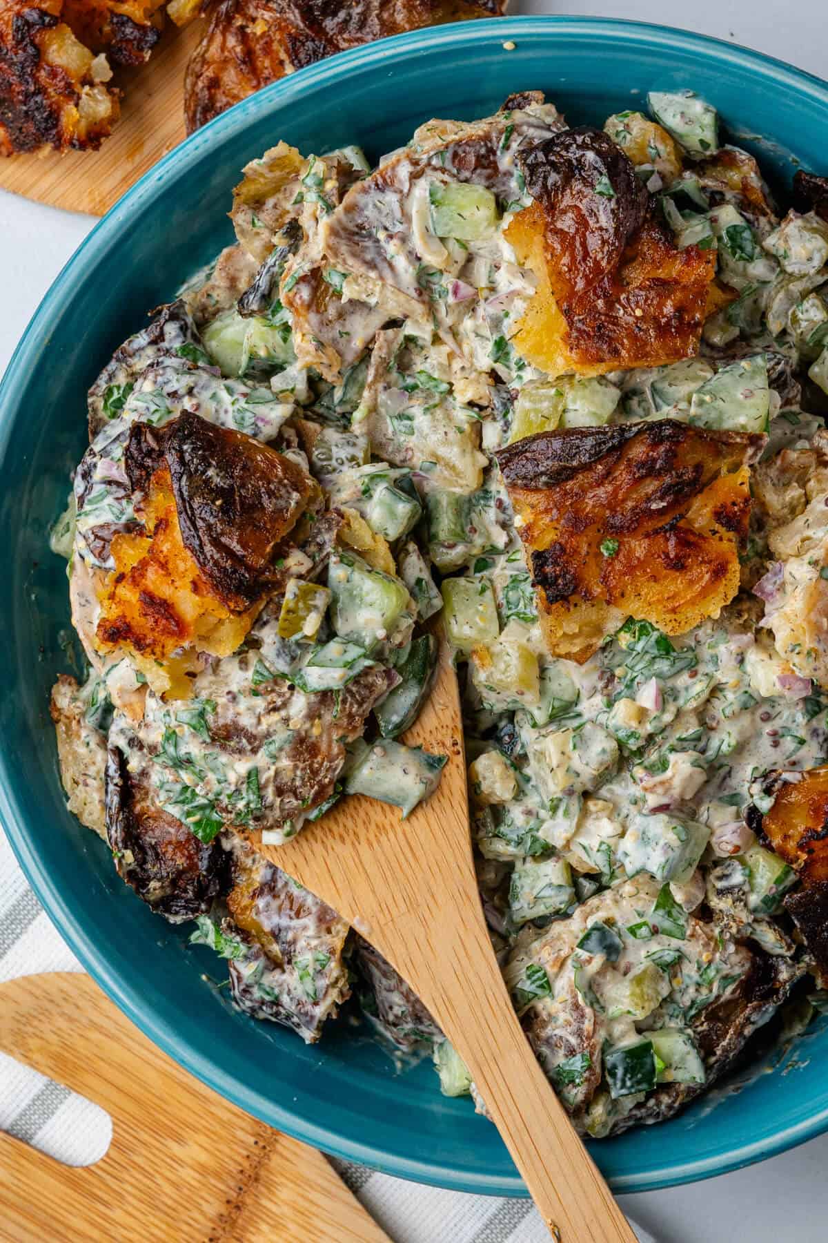 Wooden spoon in a bowl of smashed potato salad