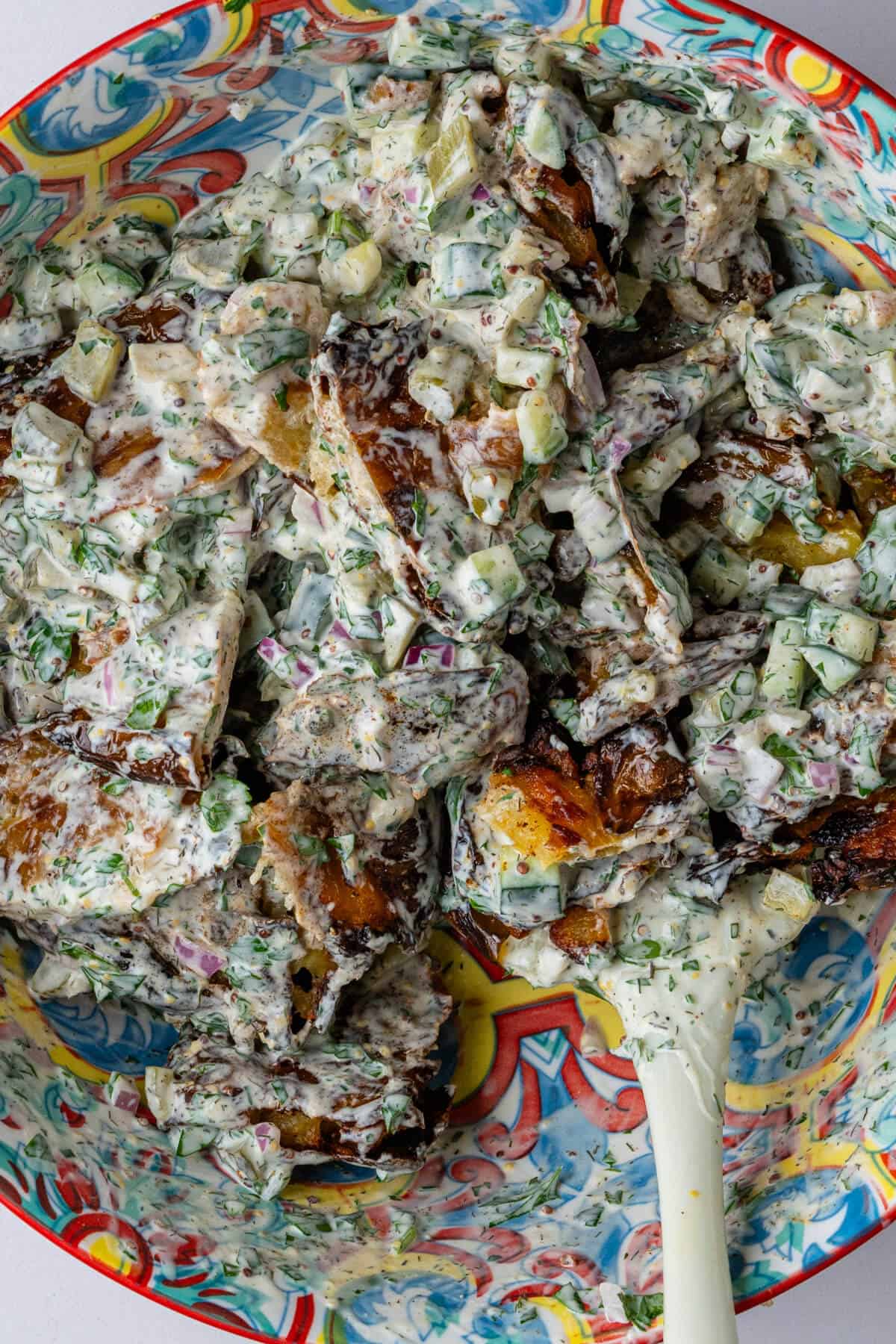 Potatoes mixed into the dressing in a large bowl