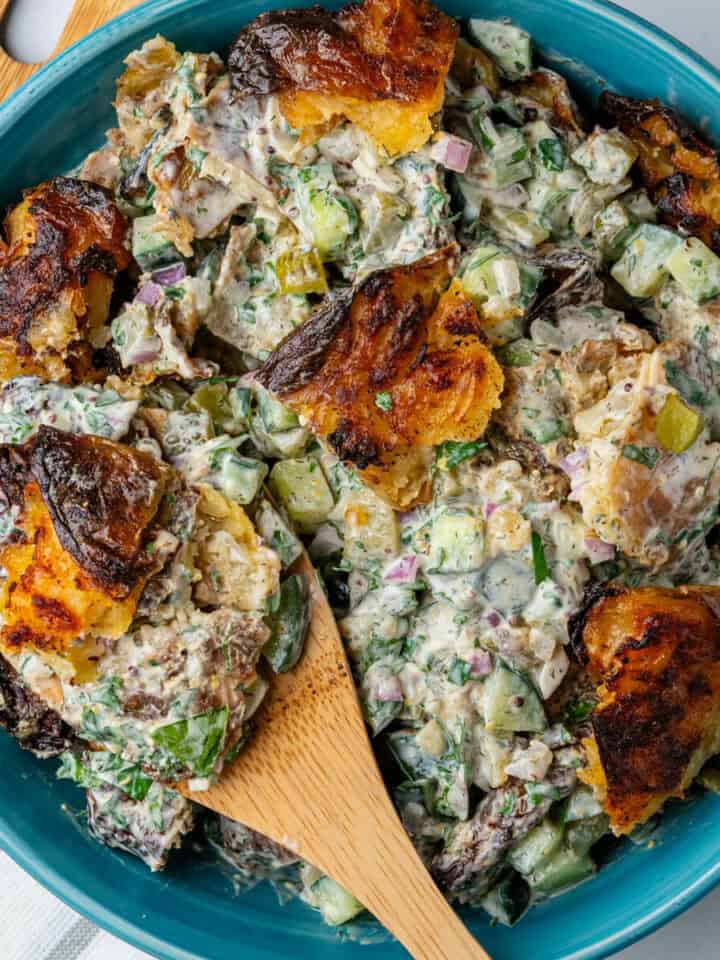 Crispy Smashed Potato Salad in a bowl with wooden spoon