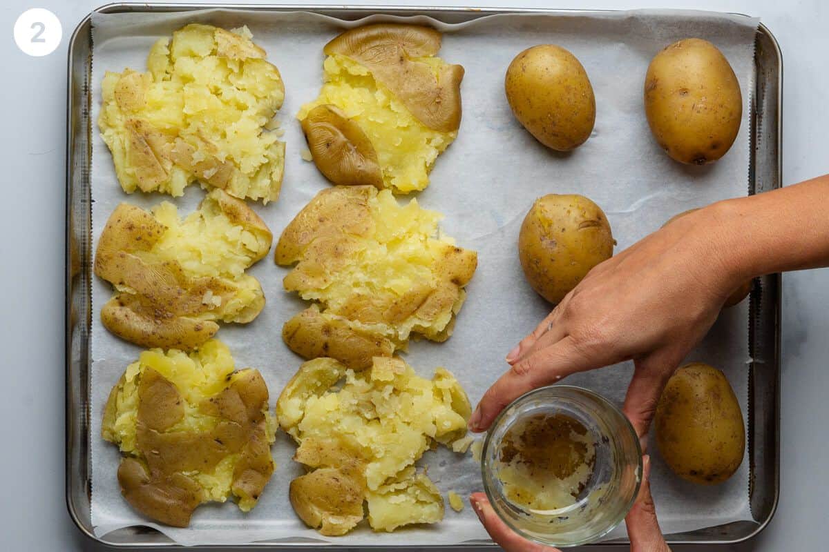 Potatoes being smashed with a glass on a tray