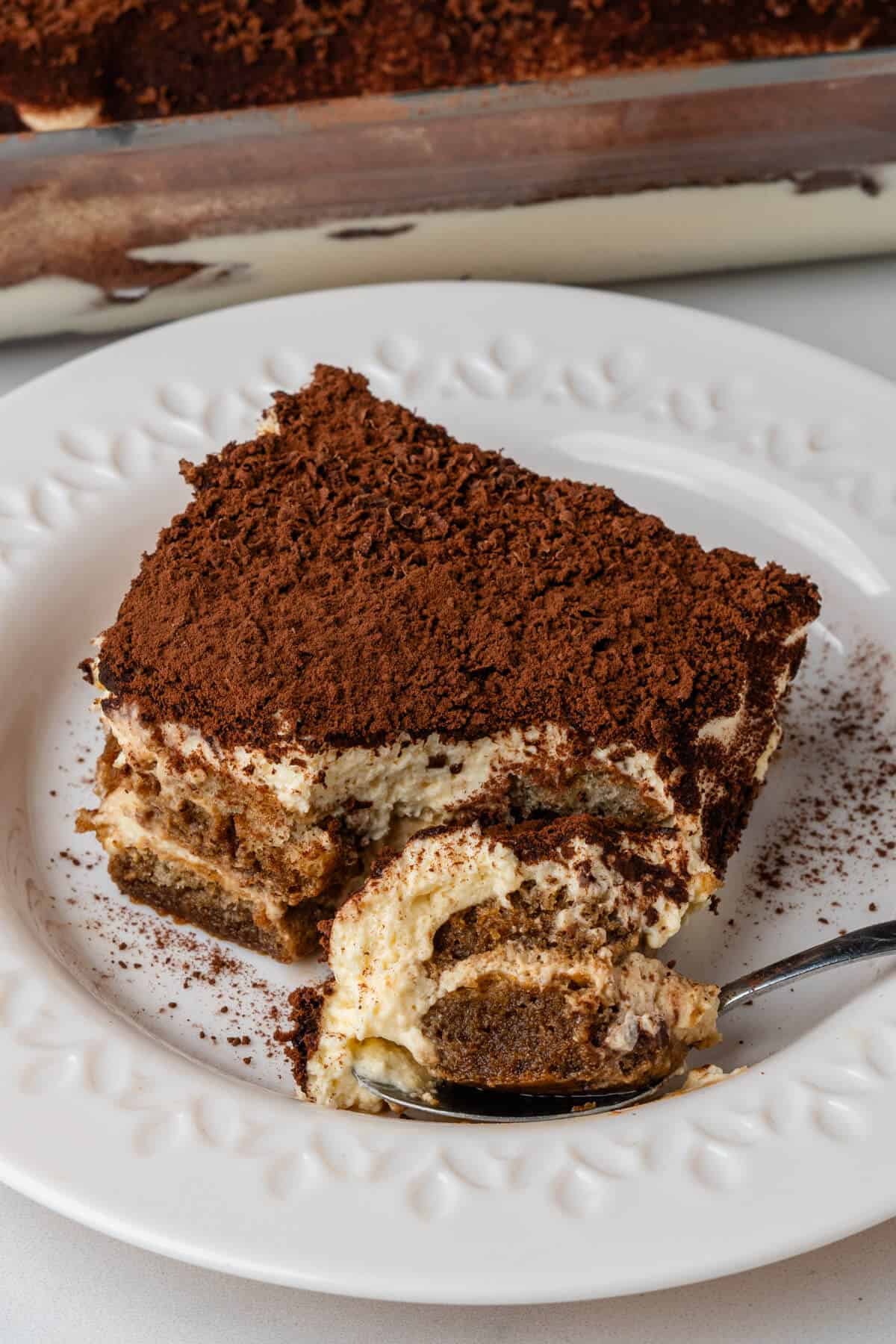 Piece of tiramisu on a plate with a spoon