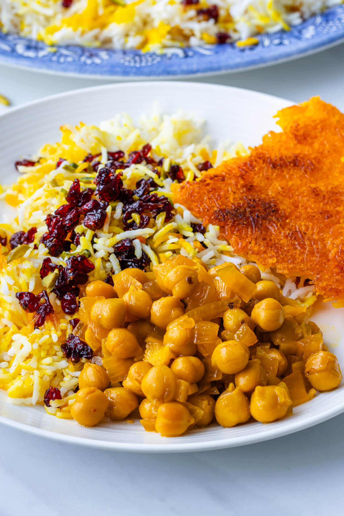 Chickpea stew served on a plate with crispy tahdig and zereshk polo