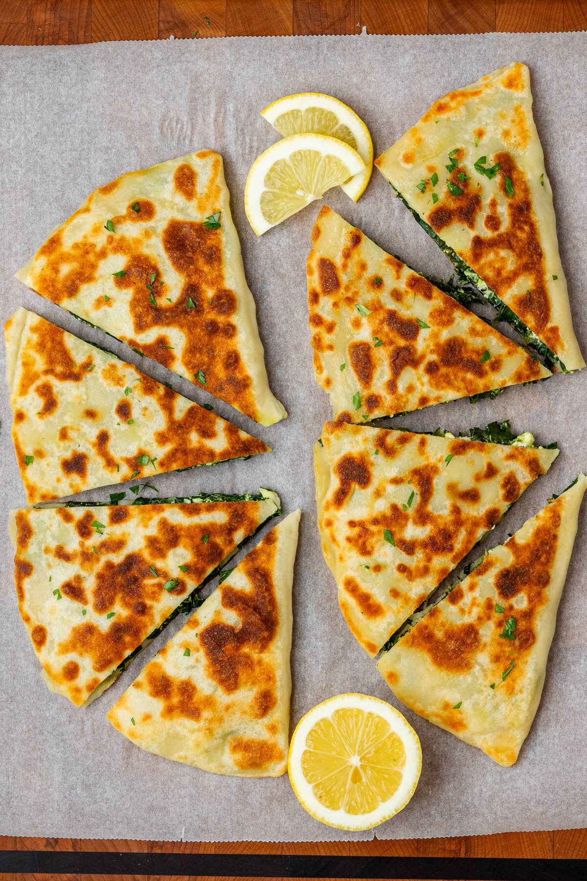 Gozleme cut into pieces on a cutting board with lemon on the side