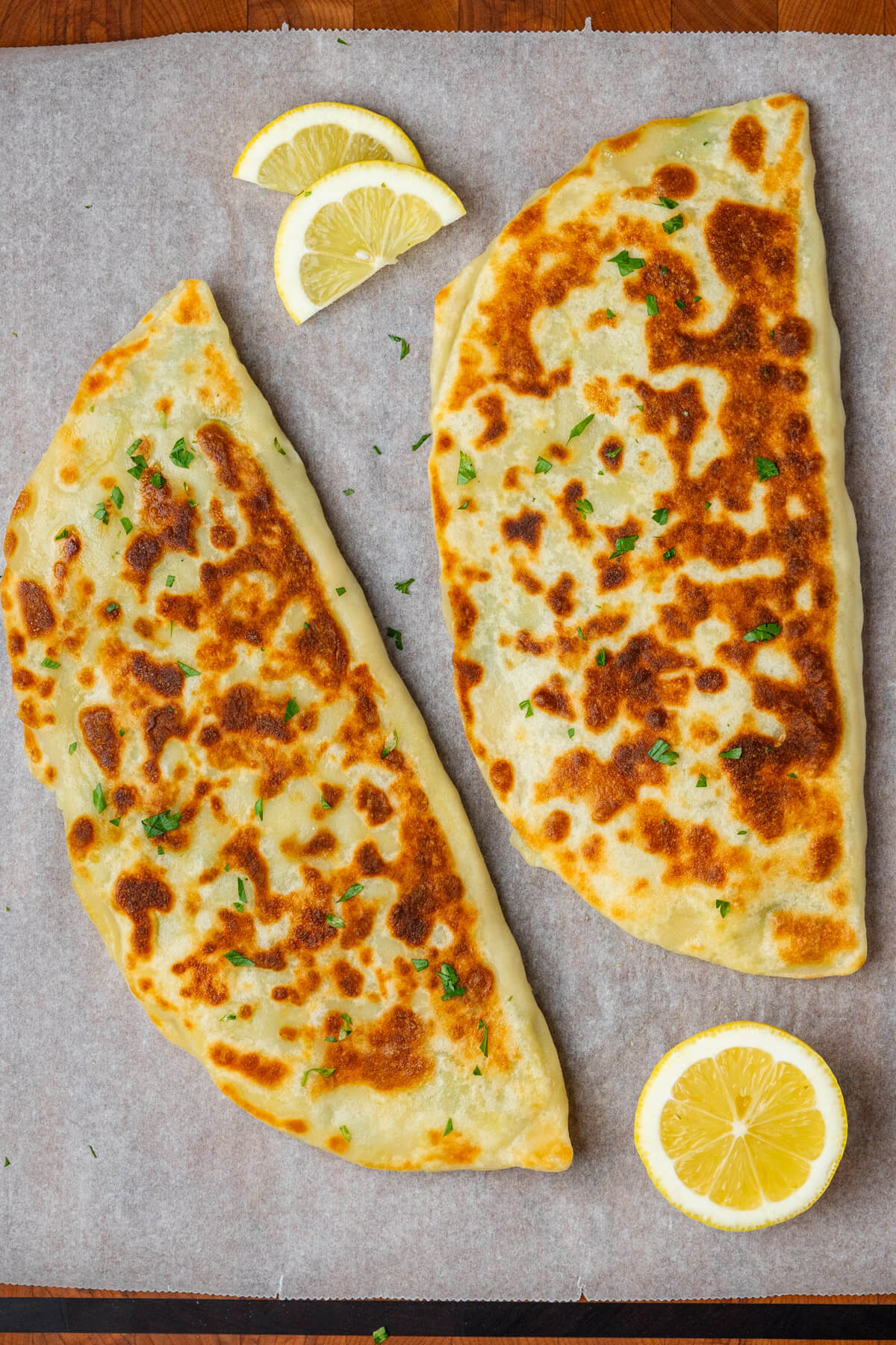 Two pirces of gozleme on a cutting board before being cut