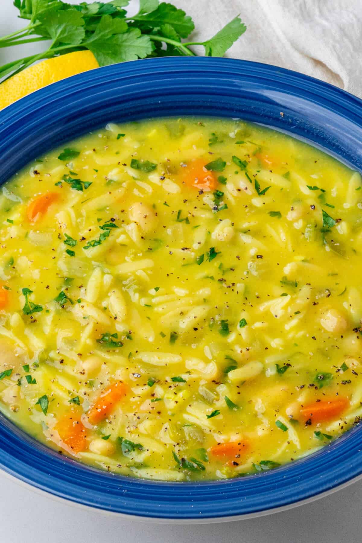 Lemon orzo soup in a bowl with parsley and pepper on top