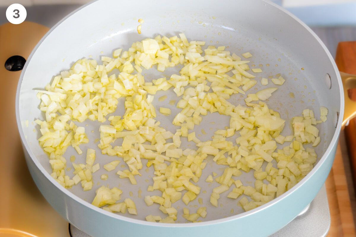 Onions being sautéed in a large pan