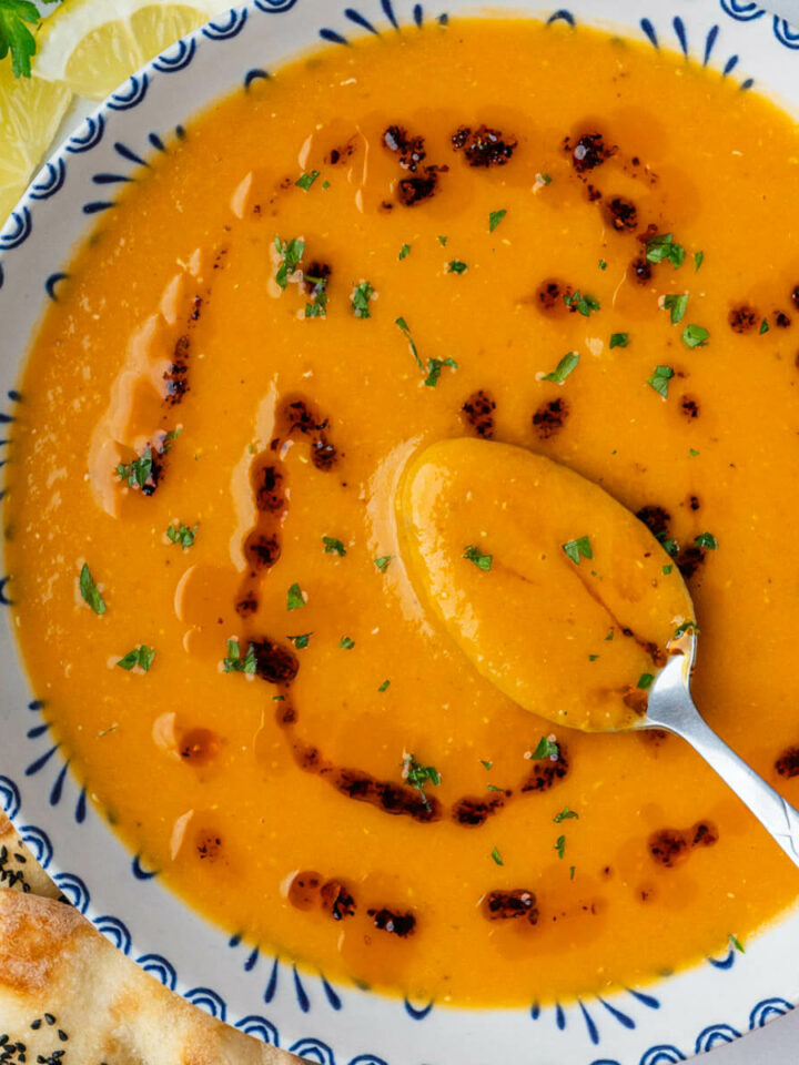 Spoon in a bowl of Turkish lentil soup (Mercimek Çorbası) and Aleppo pepper oil