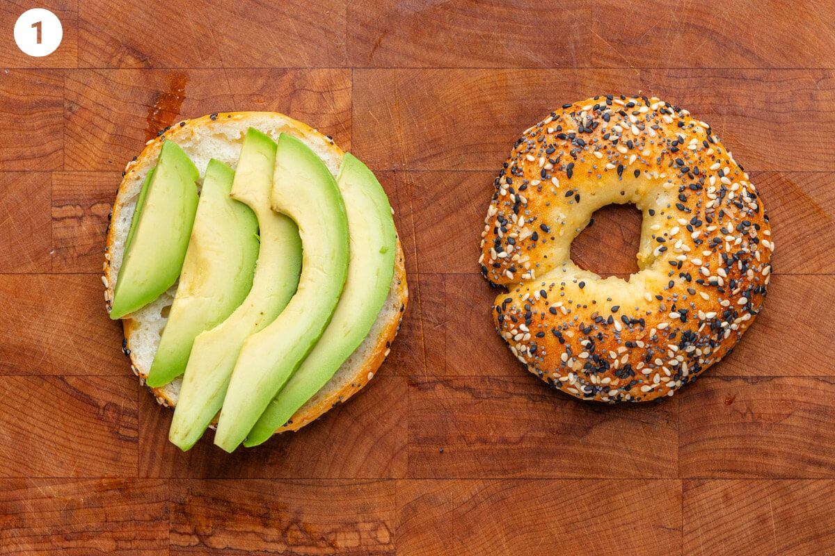 Sliced avocado placed on one half of a breakfast bagel