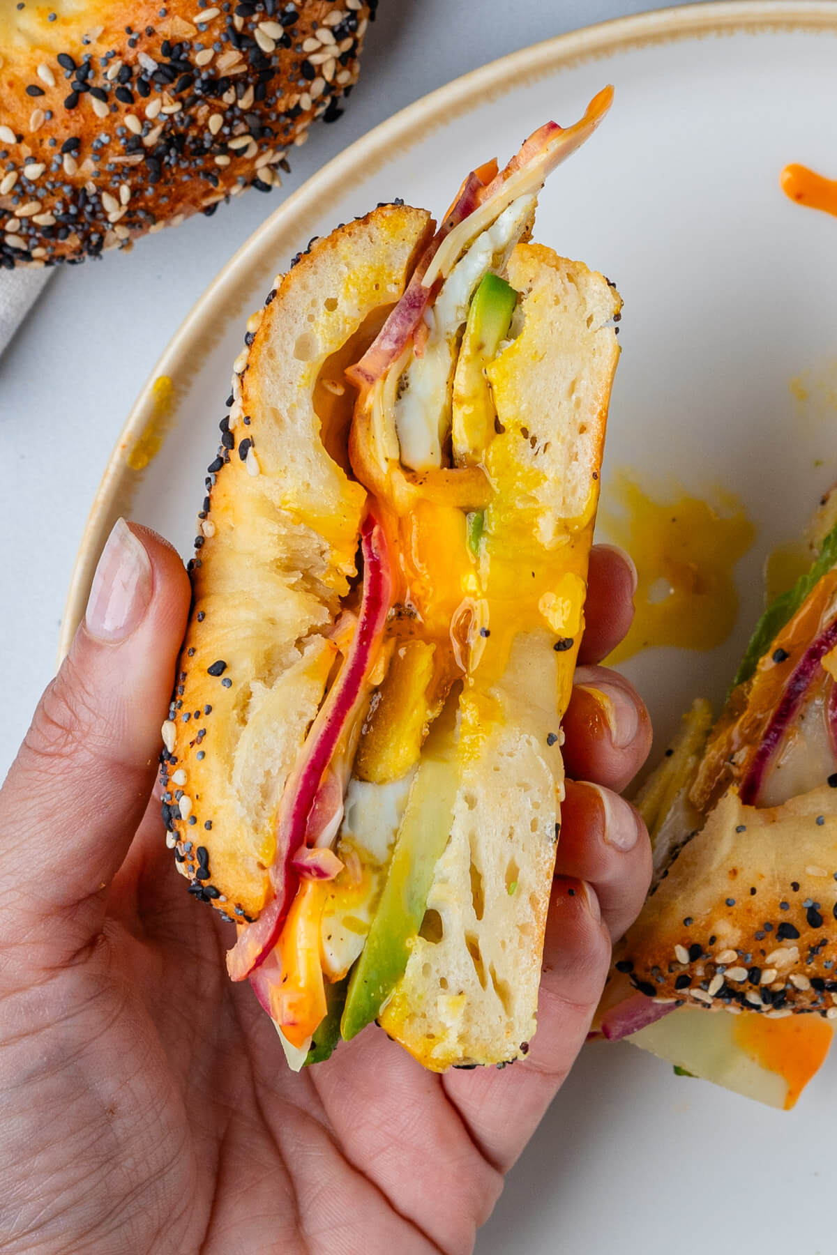 Half piece of bagel held in hand to show the inside