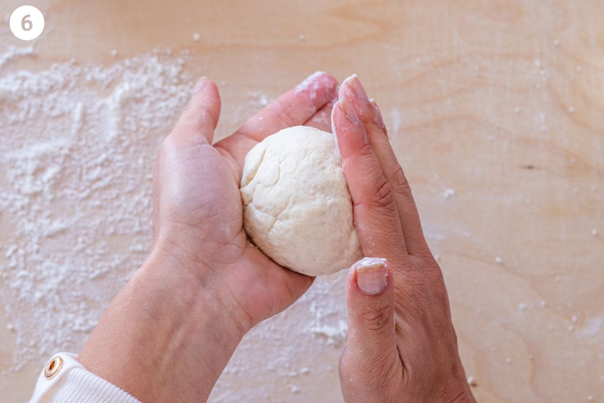 One dough piece being rolled into a ball