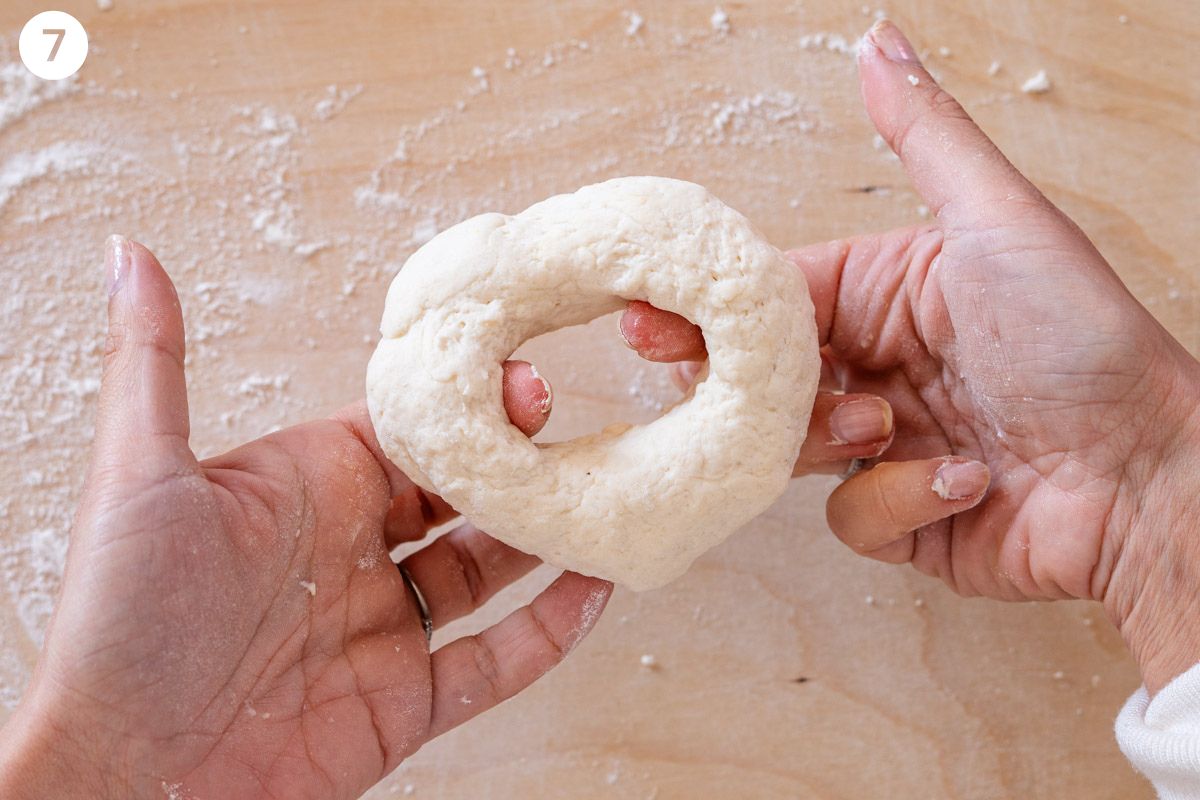 Hands making dough into bagel shapes