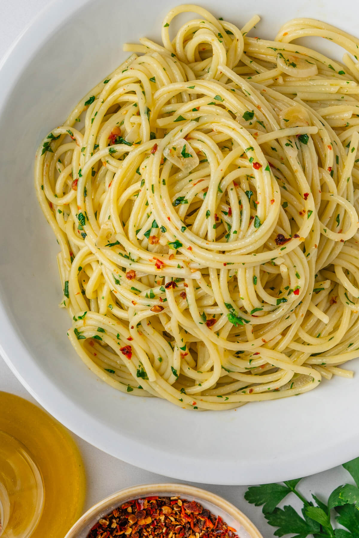 Aglio e Olio in a bowl with chilli flakes on the side