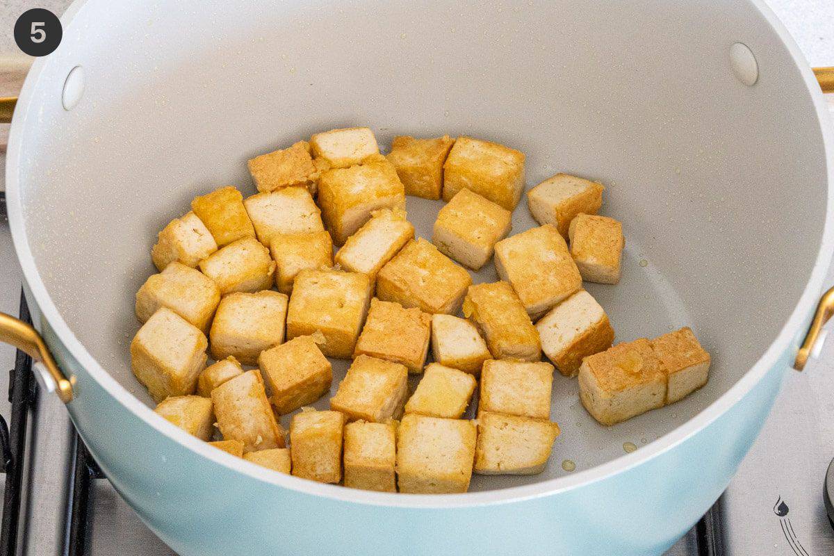 Tofu being sautéed in a large pot