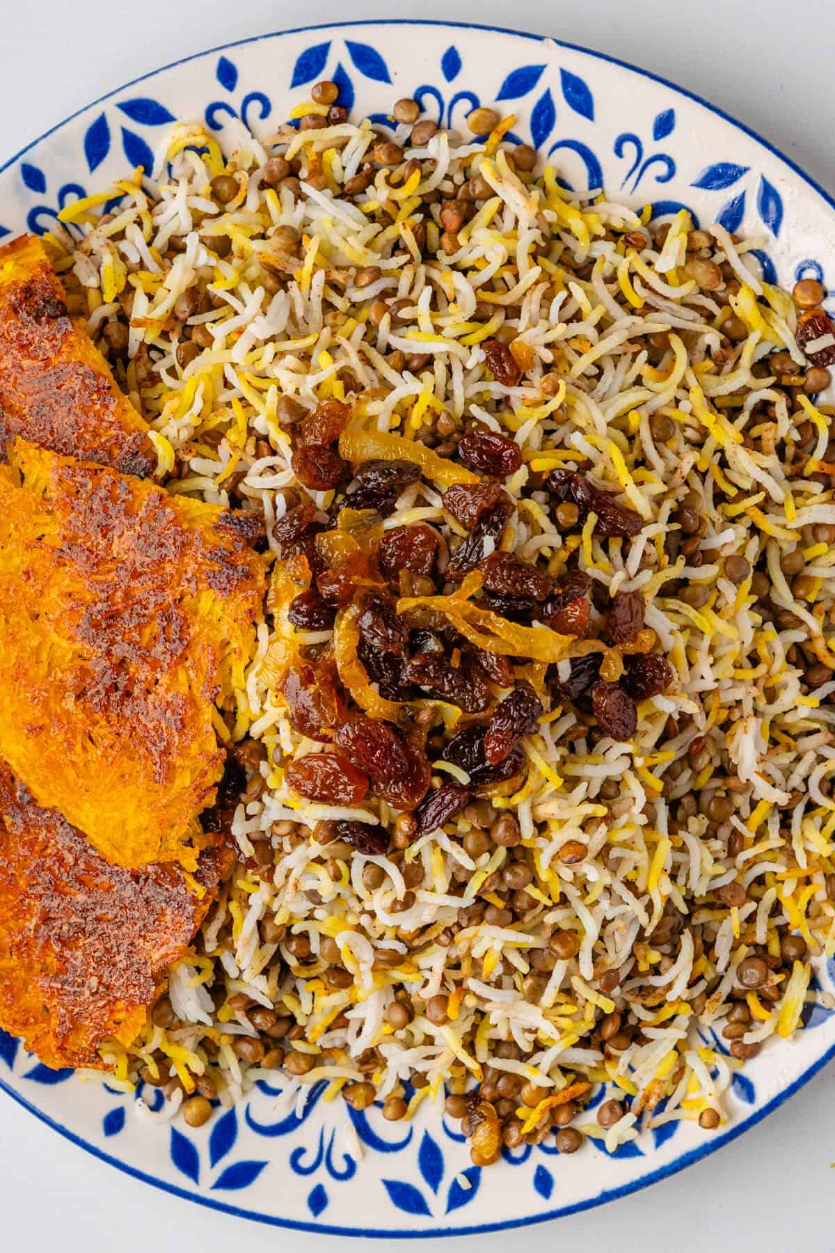 Plate of Adas Polo served with tahdig caramelised onions and dried fruits