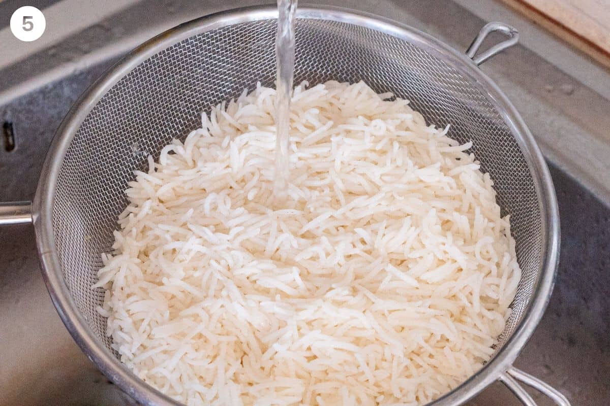 Rice drained in a colander and rinsed under water