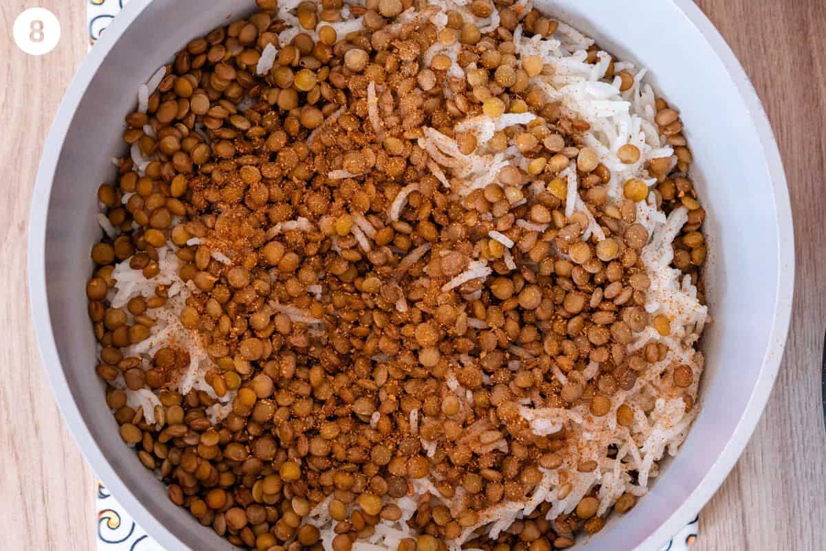 Layers of rice and lentils added to a pot with spices