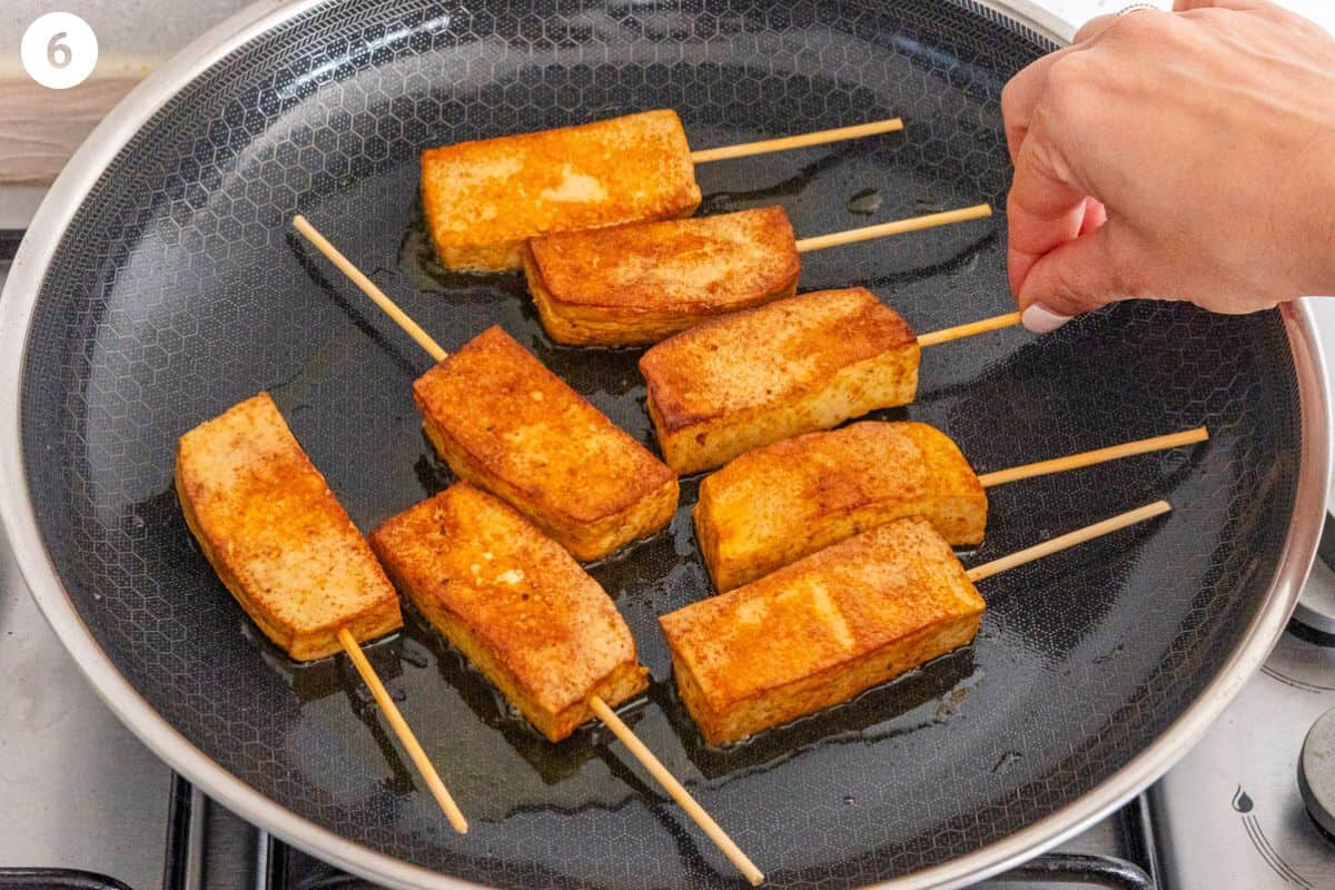 Pieces of tofu being flipped to cook the second side