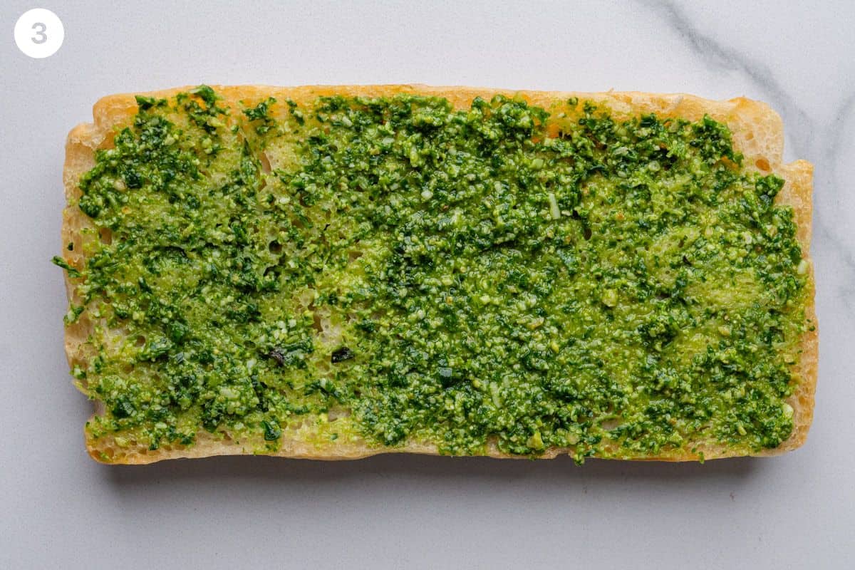 Pesto spread on one side of the focaccia bread