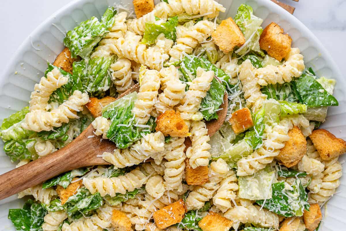 Caesar pasta salad topped with croutons and parmesan cheese