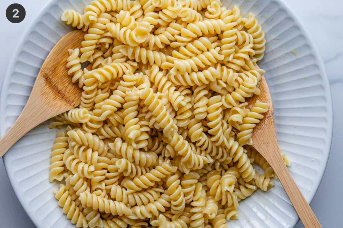 Pasta mixed with olive oil in a large bowl