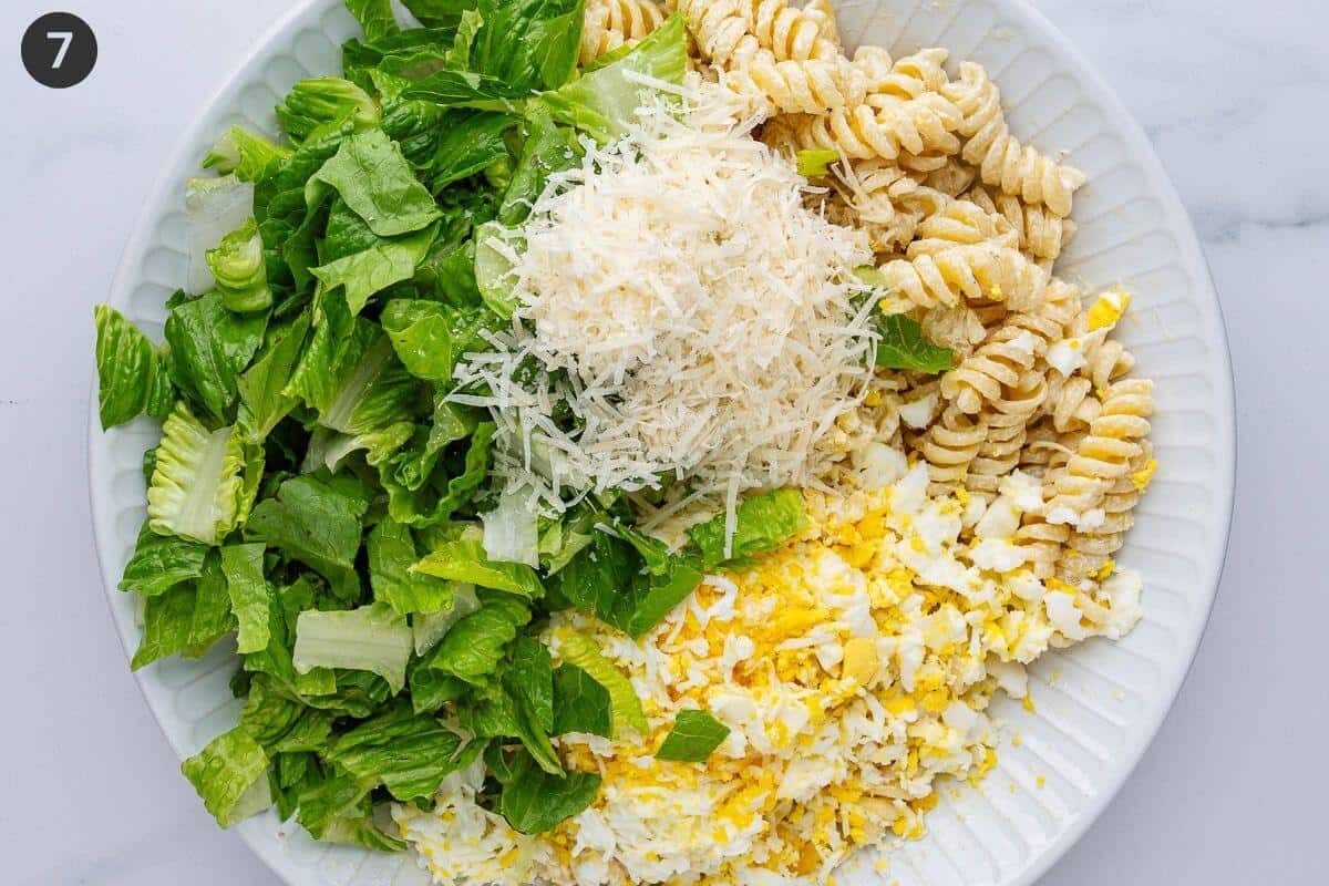 Lettuce, parmesan and boiled eggs added to pasta in a bowl